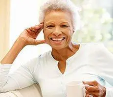 Elderly woman smiling with a cup.