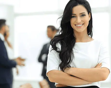 1797089 Smiling woman in office setting, arms crossed.