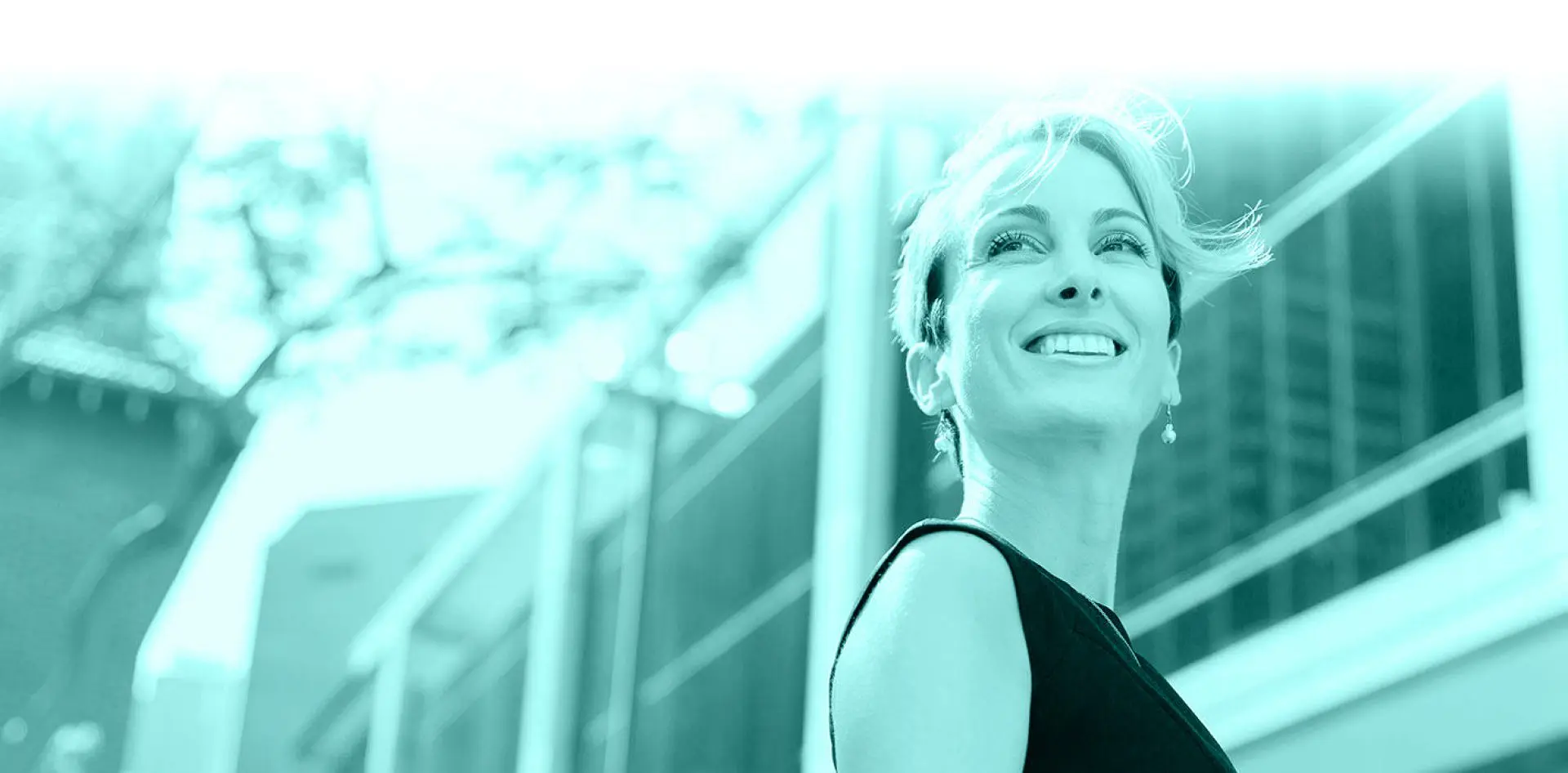 hero 01 Smiling woman standing outside modern building.